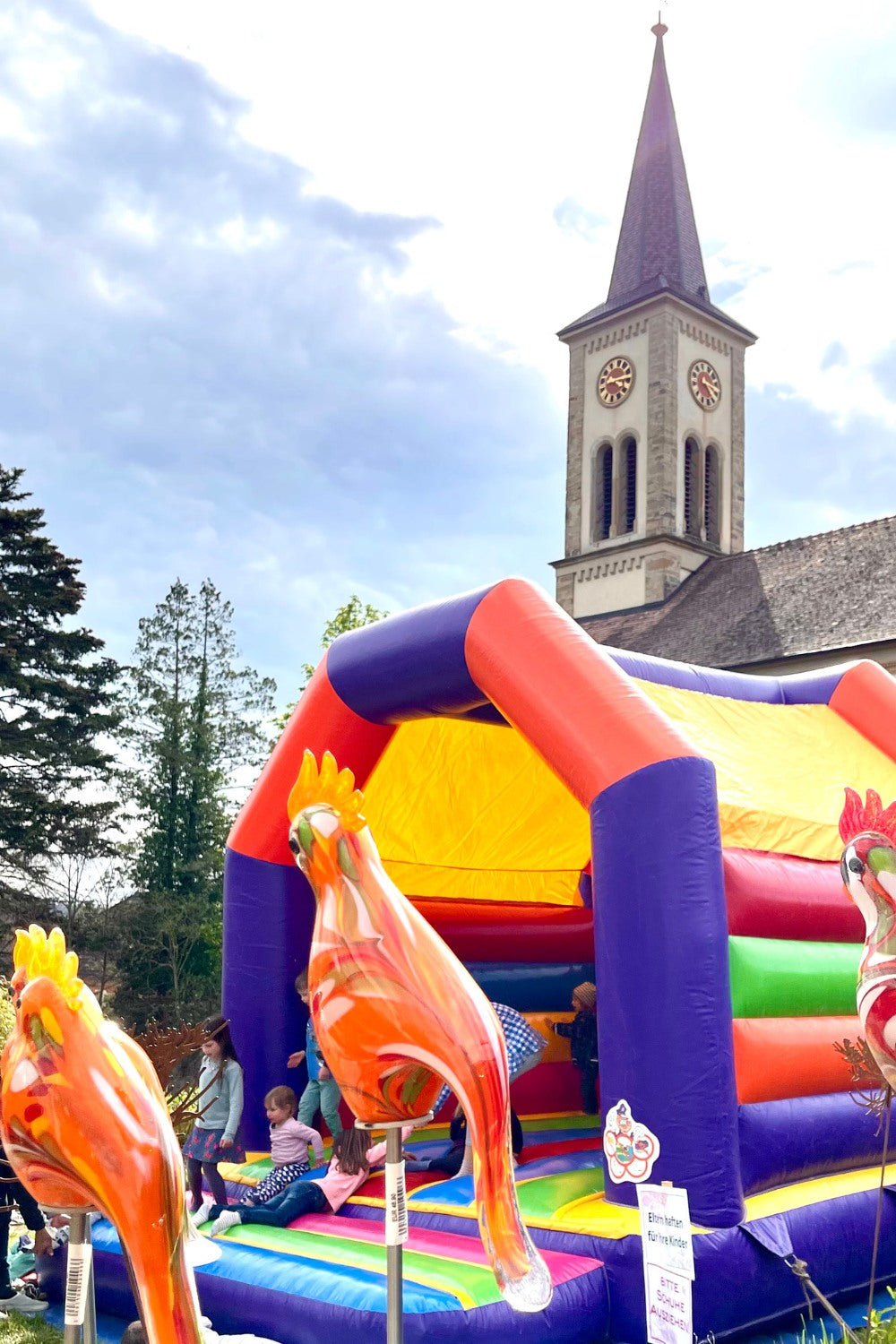 Die bunte Hüpfburg hat den Kindern besonders Spaß gemacht. Im Vordergrund sieht man orangene Papageien aus Glas.